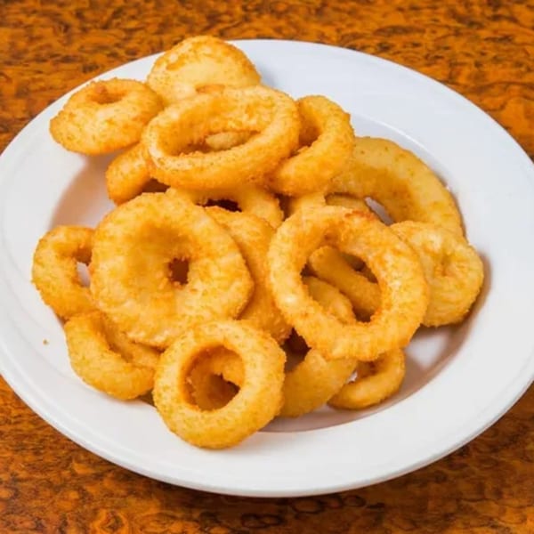 A white plate piled high with golden-brown, crispy onion rings from Georgia Diner.