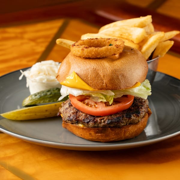 A Georgia Diner cheeseburger with lettuce, tomato, onion ring, fries, coleslaw, and pickles.