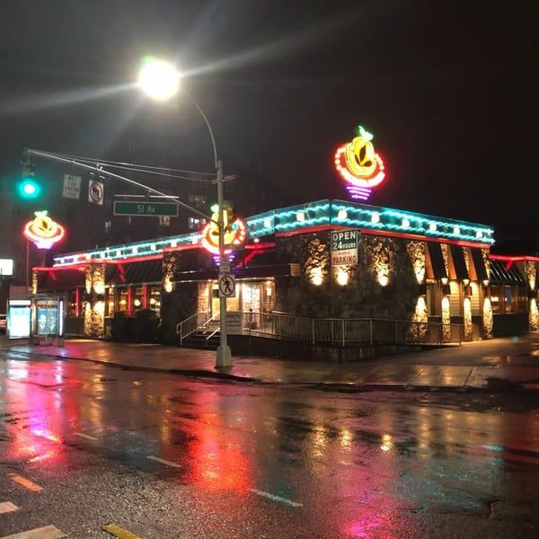 The Georgia Diner at night, illuminated by colorful neon lights reflecting on a wet street.