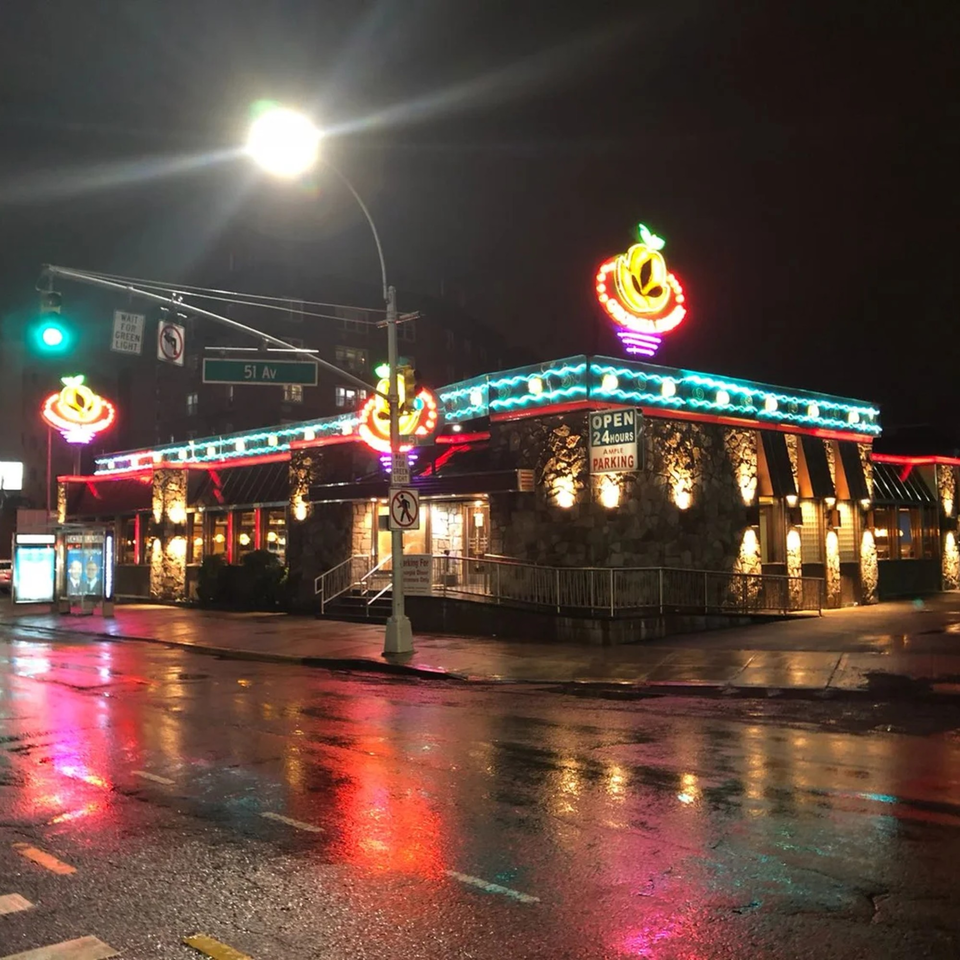 The Georgia Diner at night, illuminated by colorful neon lights reflecting on a wet street.